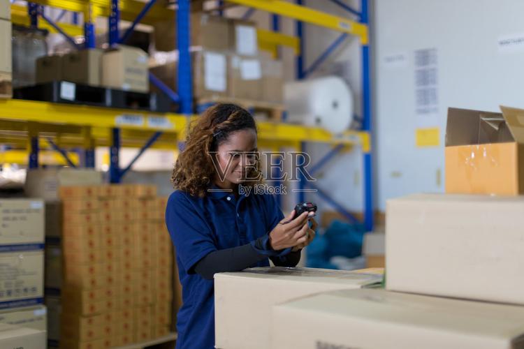 女工在工业工厂仓库使用条码机检查产品或托盘上的包裹货物检验质量